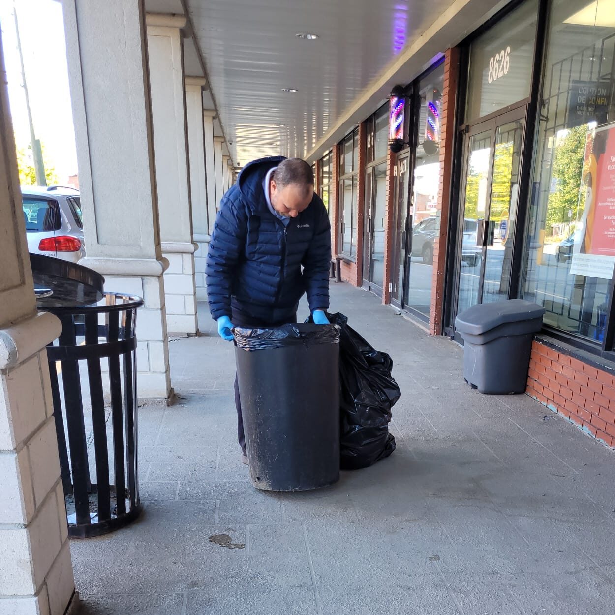 Cleaner removing trash bags outside a storefront